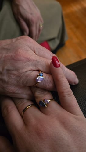 Customer's close-up of two hands together, each wearing a gold Leesha Birthstone Ring with pretty stones.