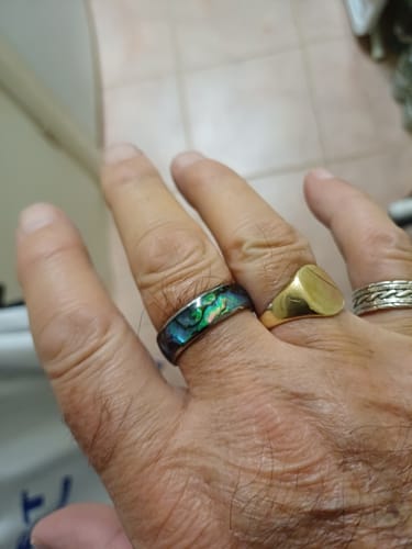Customer's hand wearing the Nerium ring, showing its iridescent abalone shell inlay.