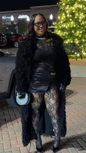 Reviewer wearing the long, black Knit Shaggy Loop Coat outdoors at night for an evening out.