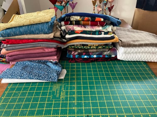 Reviewer's Box of Scraps showing several neat stacks of colorful, folded fabric on a worktable.