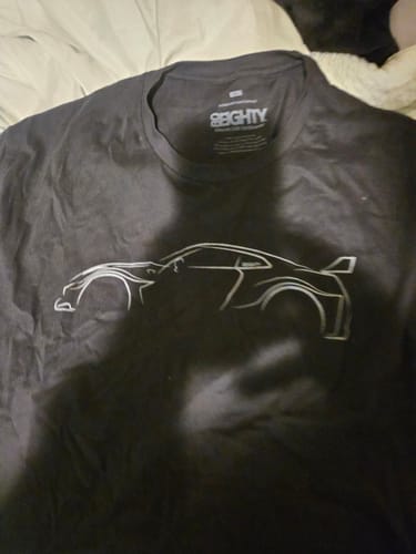 Customer's black 80Eighty DCG #84 Shirt laid flat, showing the white outline graphic of a car.