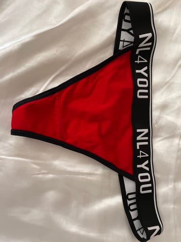 Reviewer's red thong with a wide black NL4YOU branded waistband, laid out on a white surface.