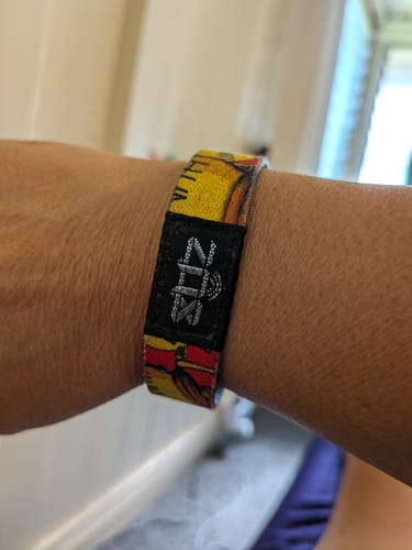 Close-up of a reviewer's wrist wearing the yellow F&F Spectra Interactive Bracelet with a Winnie the Pooh design.