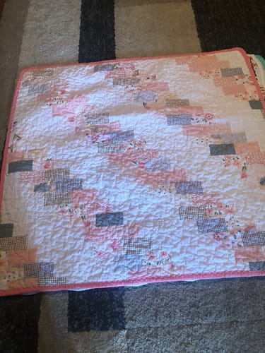 Customer's finished patchwork quilt made with the Mrs Quilty Subscription Box, featuring pink, grey, and white fabrics.