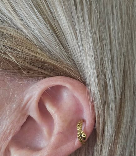 Close-up of a customer's ear wearing the gold-plated Medusa Snake Earring in the cartilage.