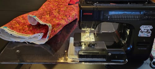 Customer's clear Sew Steady Extension Table fitted to a black Janome sewing machine, supporting a large piece of patterned fabric.