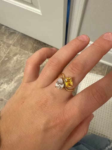 Customer wearing the gold Navae Birthstone Ring with its clear pear-cut and yellow radiant-cut stones.