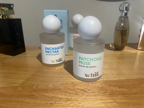 Customer's bottle of Patchouli Muse perfume on a wooden surface, next to other fragrances.