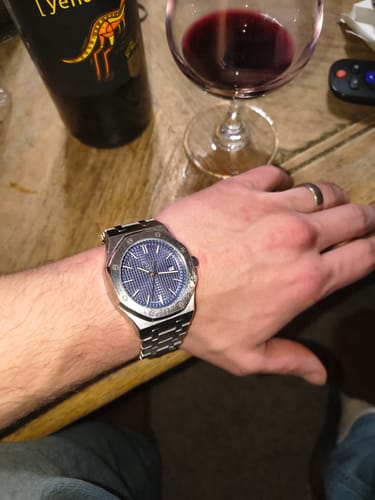 Customer's silver-toned Lucky Fours® Oceanus watch with a blue dial shown on their wrist indoors.