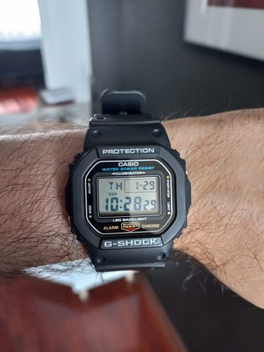 Reseñador mostrando su reloj Casio G-Shock DW-5600UE-1JF negro en la muñeca.