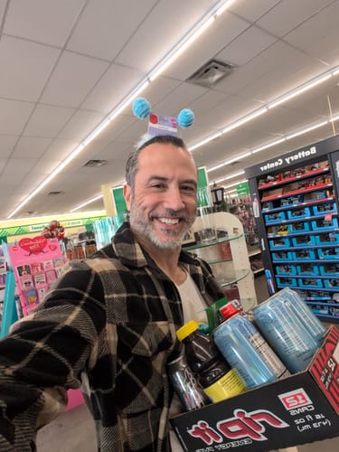A happy reviewer wearing a playful headband smiles for a selfie while shopping in a store.