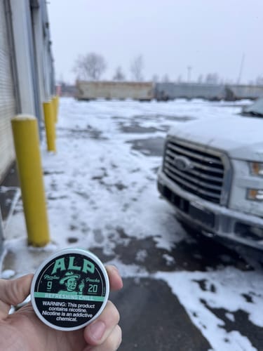 Customer holding a can of Refreshing Chill Nicotine Pouches in a snowy, outdoor setting.