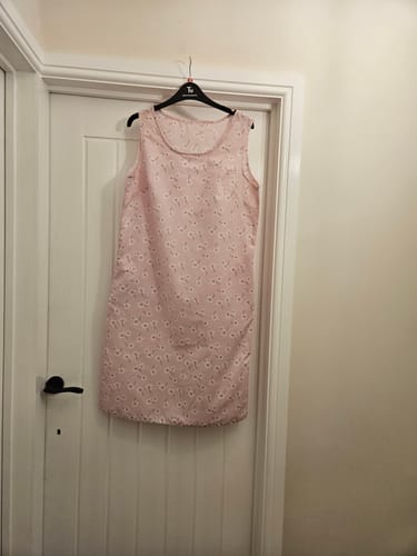 Customer's handmade pink dress using the White Flowers and Polka Dots Polycotton Fabric, hanging on a door.
