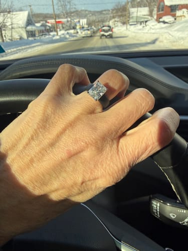 Customer's hand on a steering wheel wearing the bold Silicone Ring with a shiny emerald-cut stone.