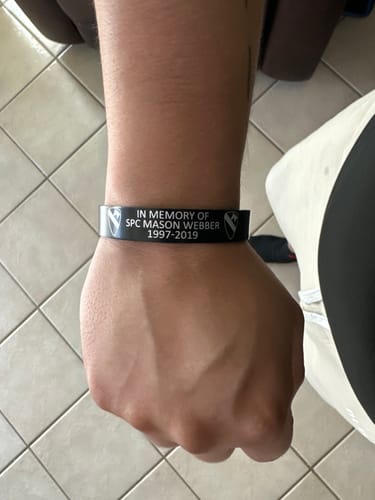 Reviewer's wrist wearing a customized black bracelet with memorial text for SPC Mason Webber.