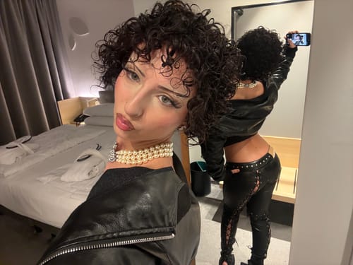 Reviewer taking a mirror selfie showing the front and back of the black Vice Pant. The low-rise pants have lace-up sides.