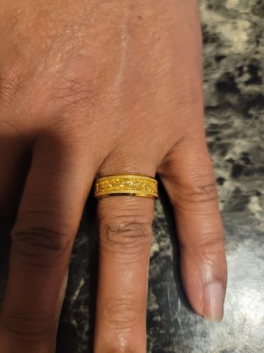 A customer's hand wearing the gold Aureum ring, showing off its textured foil inlay.