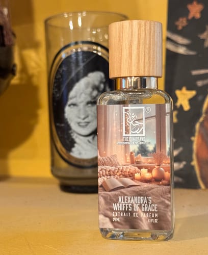 Reviewer's Alexandra's Whiffs Of Grace perfume with a wooden cap, displayed on a yellow surface.
