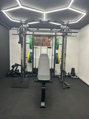 Kundenfoto des schwarzen Edge A FlexProtect Bodens, der in einem Heim-Fitnessstudio unter Geräten verlegt ist.