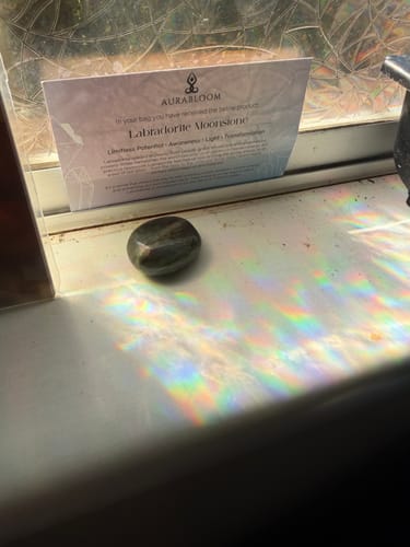 Customer's dark Labradorite Moonstone sitting on a windowsill, casting a colorful rainbow reflection.