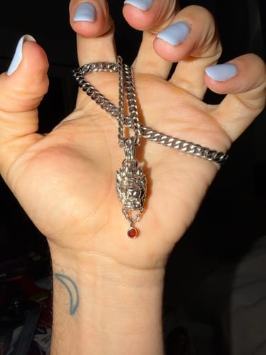 A customer holds the silver Leo Zodiac Pendant in their hand, showing the detailed design and red gem.