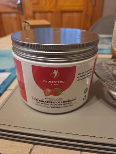Reviewer's tub of strawberry-flavored Cholestero-Low supplement sitting on a home table.