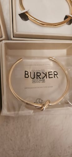 Close-up of the reviewer's Eternity Gold Bracelet with a knot detail, shown in its packaging.