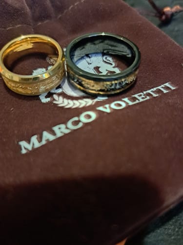 Customer's black Titanfall ring with gold flake inlay, shown next to another gold-colored ring on a velvet pouch.