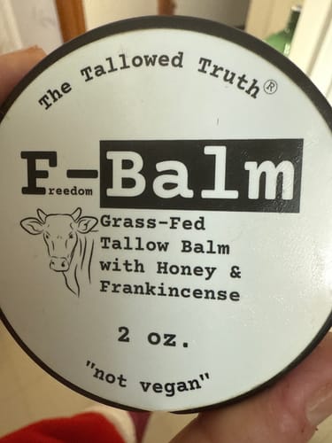 Customer holding the round tin of F-Balm, showing the black and white label on the lid.