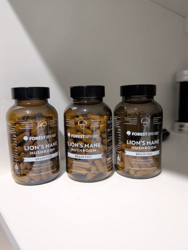 Customer's three full bottles of Lions Mane Mushroom Capsules lined up on a white shelf.