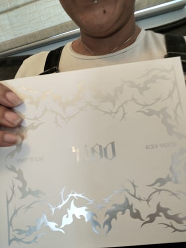 A reviewer holds up the white packaging for the STRAY KIDS TAPE ALBUM, showing its silver foil designs.