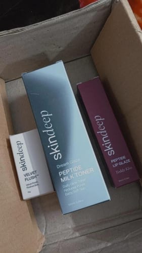 Customer's unboxing photo showing the Peptide Lip Glaze box in shade Teddy Kiss with other Skindeep products.