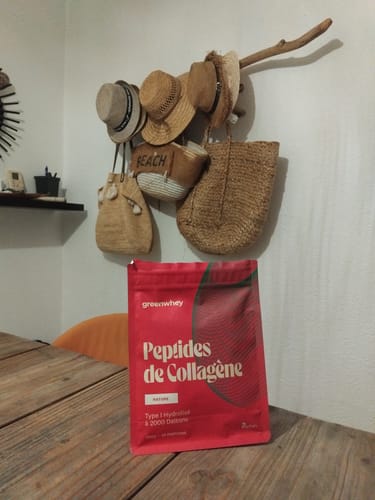 Sachet rouge de Peptides de Collagène d'un client, posé sur une table en bois.