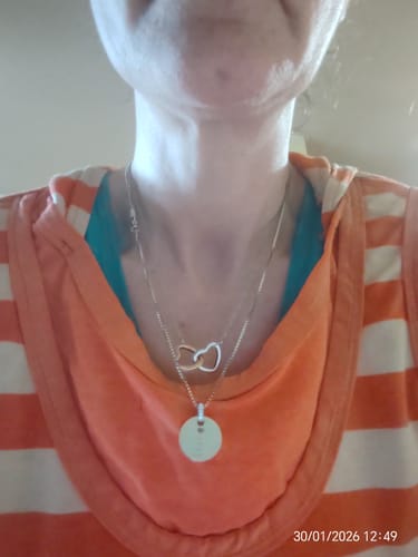 Reviewer's close-up of the Double Heart Brass Necklace with two-tone hearts being worn.