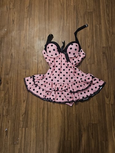 Customer's pink polka dot halter swimsuit laid out on a wooden floor.