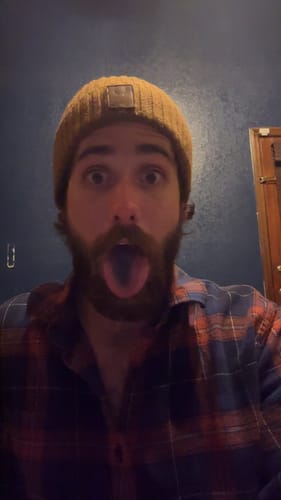 Reviewer with an energetic look shows their tongue stained blue after using Blue Cannatine™.