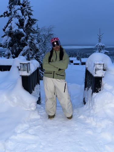 Reviewer standing with arms crossed while wearing the baggy Ice Blue Snow Pants in a snowy landscape.