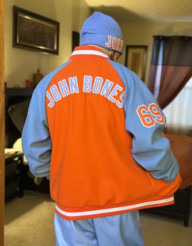 Rear view of a customer in the custom light blue sweatpants and a personalized orange and blue jacket.