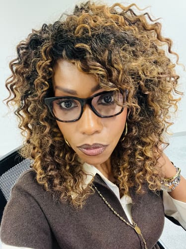 Reviewer wearing her curly Freetress Beach Curl crochet braids in a blended blonde and brown style.