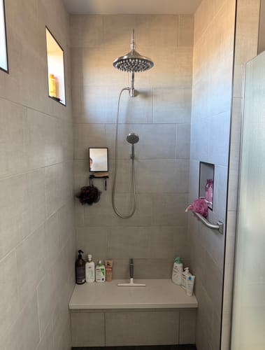 Reviewer's Handheld Shower Head Set installed in a modern tiled shower below a larger rainmaker-style shower head.