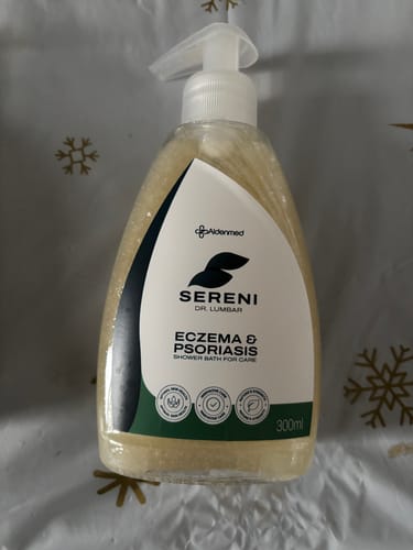 Vásárló mutatja a Sereni pikkelysömör és ekcéma tusfürdőjének átlátszó, teli flakonját.