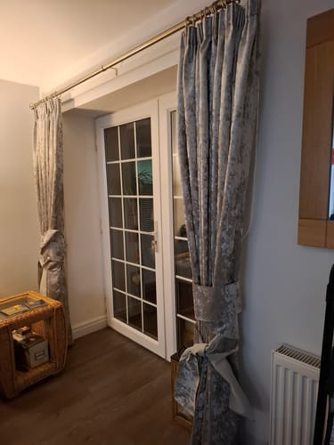Customer's full-length curtains made with silver Marble Crushed Velvet fabric, tied back from French doors.