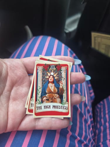 Customer holding several custom vinyl stickers with a detailed 'High Priestess' tarot card design.