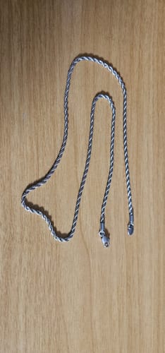 El cliente muestra la Cadena Rope de 3mm plateada sobre una superficie de madera clara.