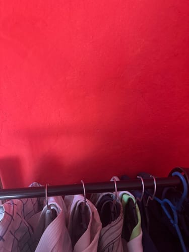 Primer plano del tubo superior del closet armable de un cliente, sosteniendo varias prendas.