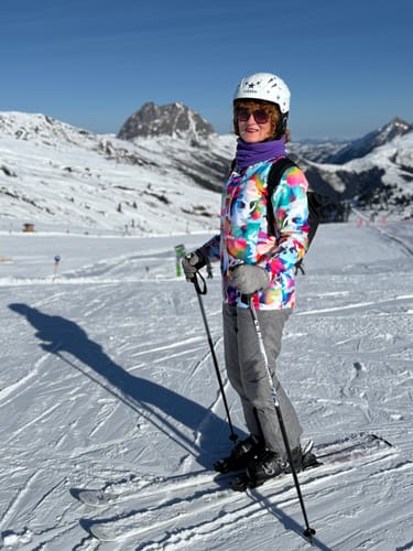 Reviewer wearing the vibrant Camo Insulated Snow Jacket while skiing on a mountain slope.