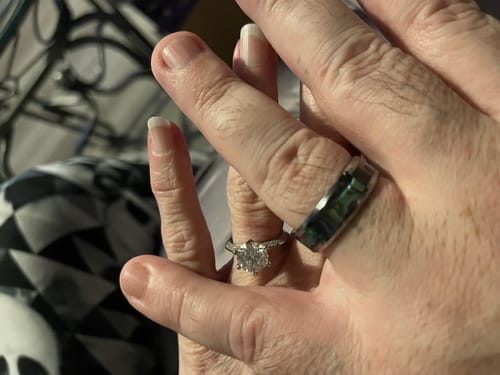 Customer's hands clasped, showing the Nerium ring with its iridescent abalone inlay.