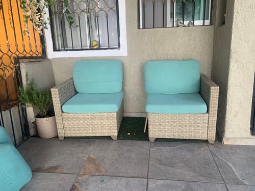 Reseñador muestra los dos sofás para exteriores de mimbre con cojines turquesa en su terraza.