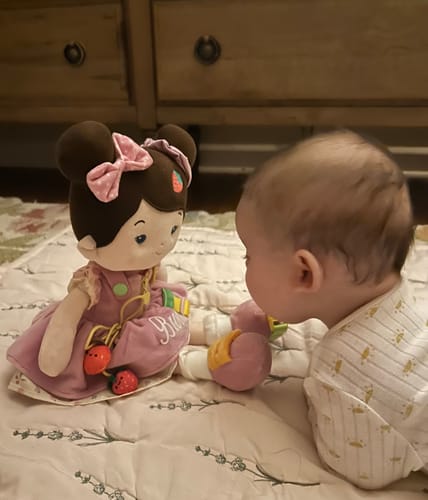 Customer's baby looking at the Personalized Jucy Girl Joosee doll while lying on a playmat.