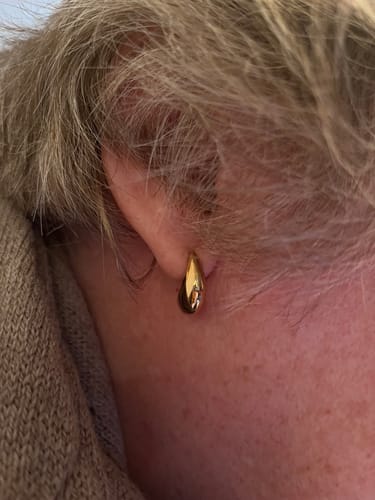 Close-up of a reviewer wearing the gold Curved Mini Hoop in their ear.